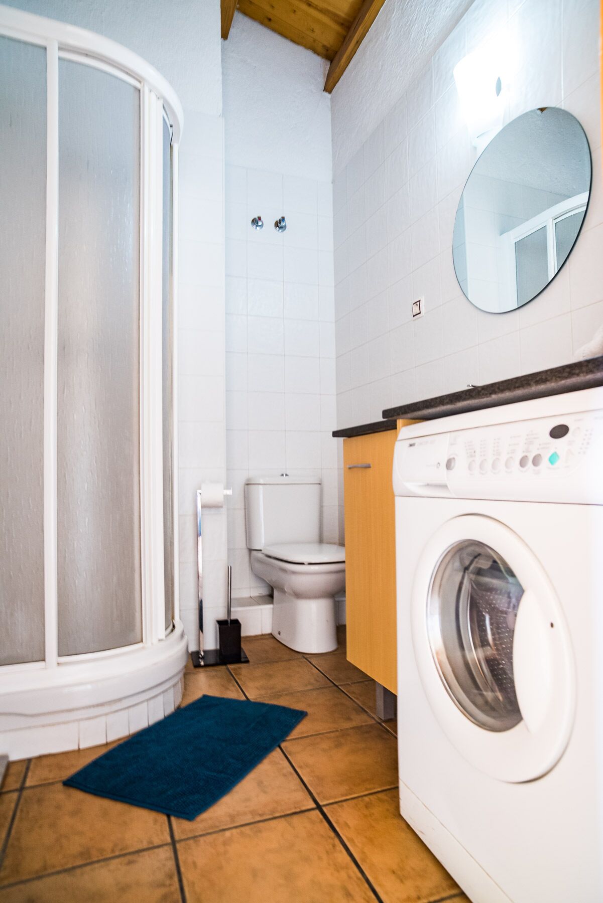 Un baño con ducha, inodoro y lavadora.