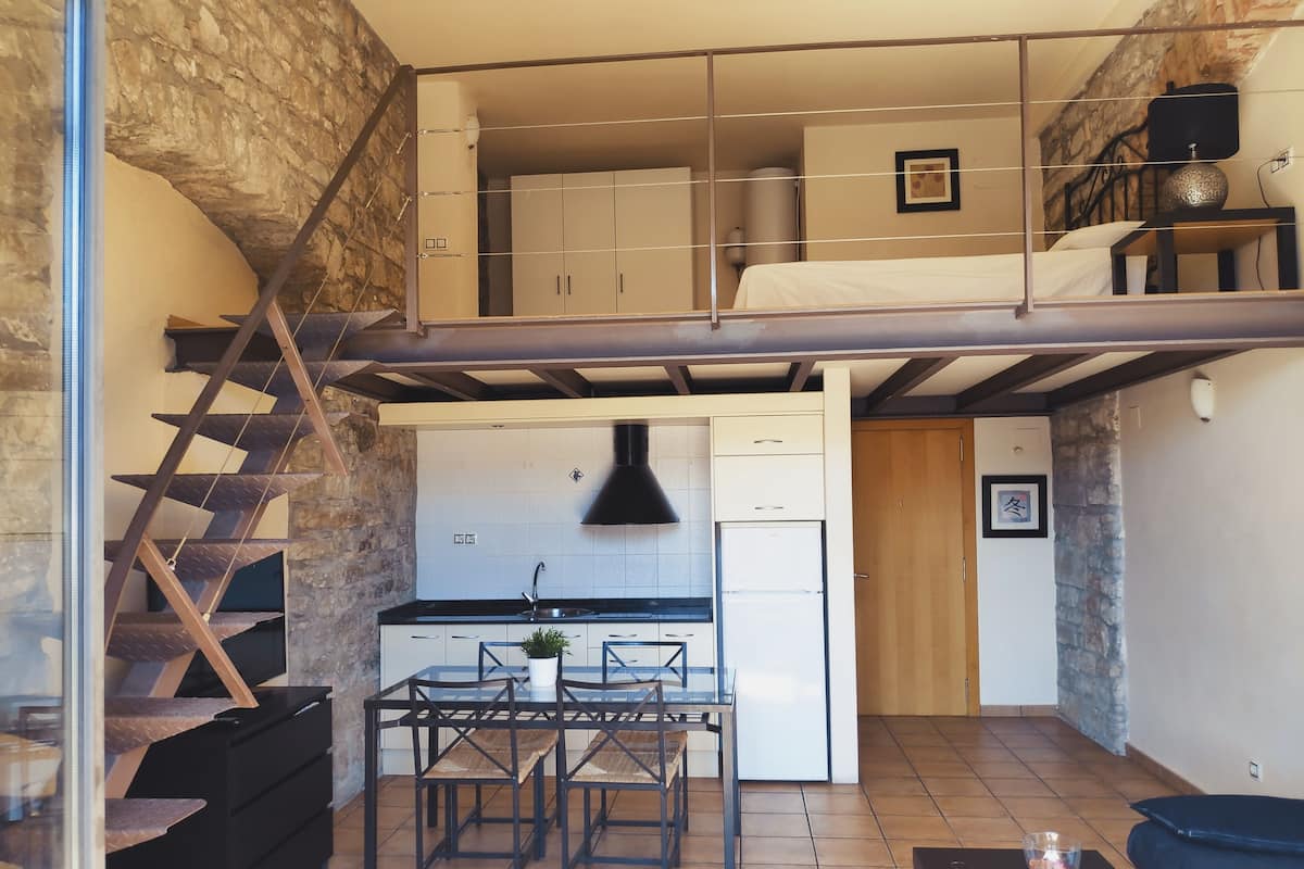 A compact apartment with a kitchen, dining area, and a loft bedroom.