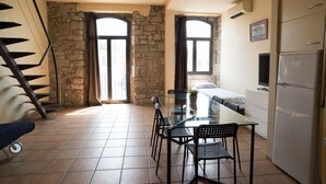 A kitchen with a dining table, chairs, a refrigerator, and a stone wall. - Urbi Apartments (Manresa)