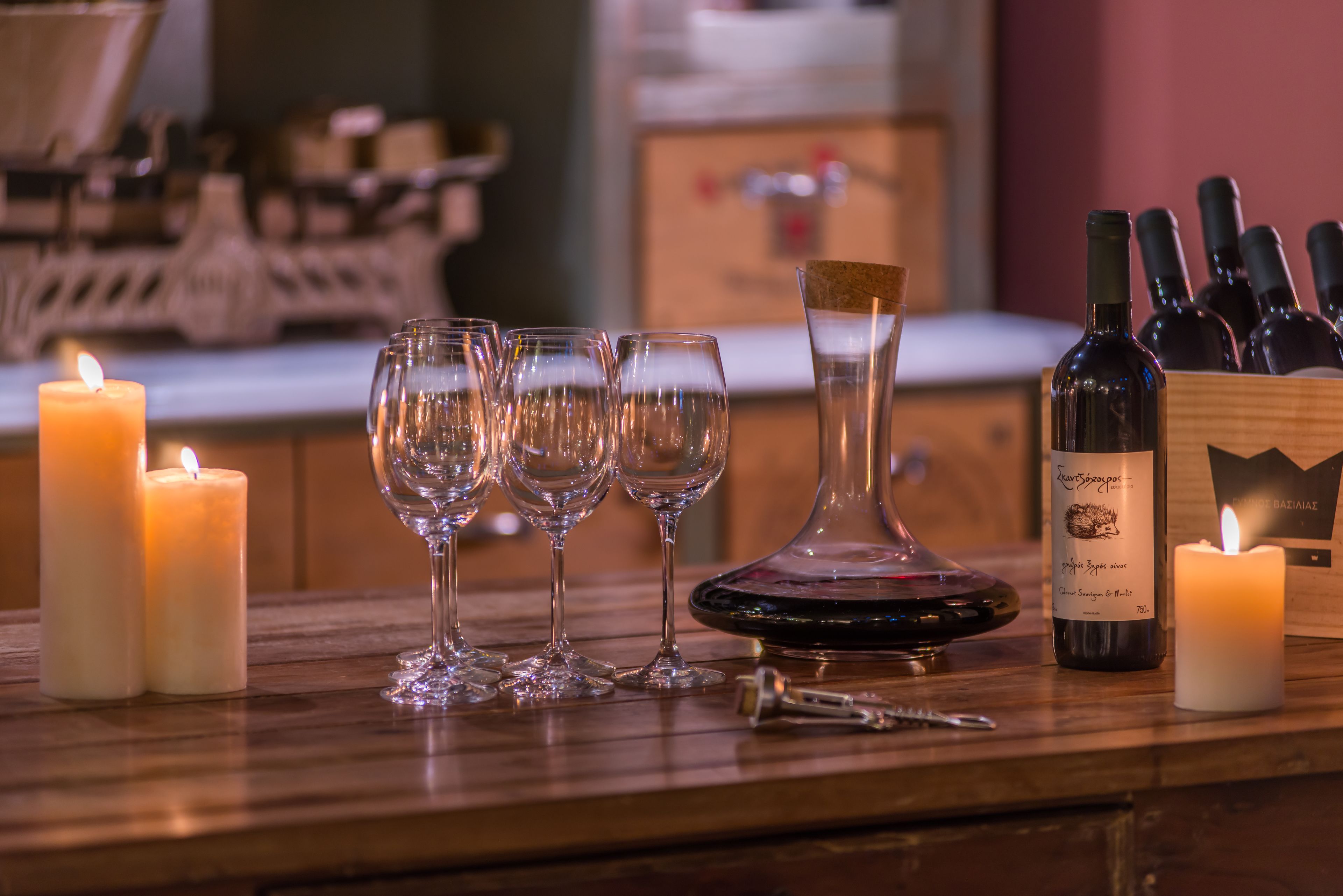 Uma área de bar com velas, copos de vinho, abridor de garrafa e garrafas de vinho.