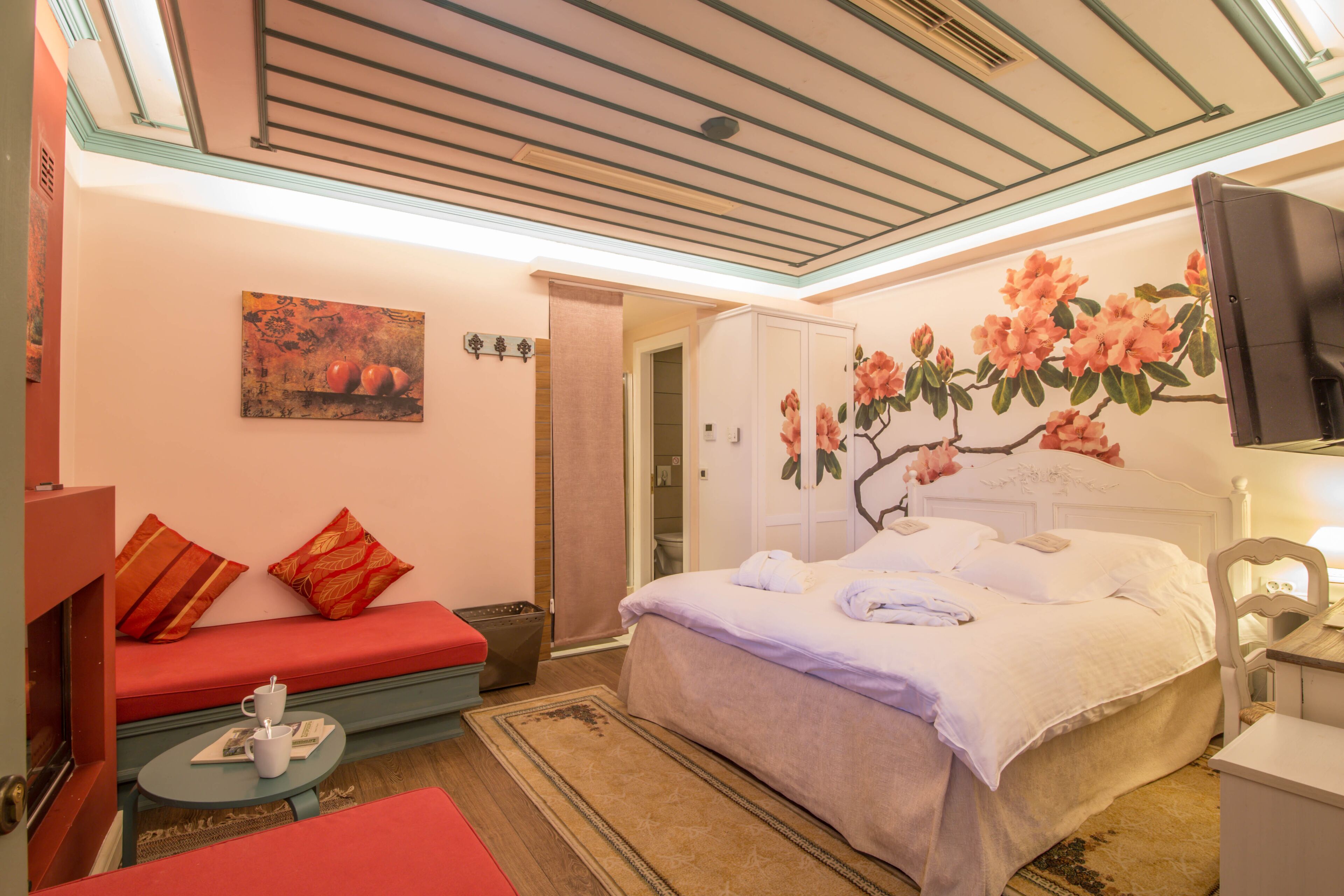 Una habitación de hotel con cama, sofá, televisión y un cuadro en la pared.