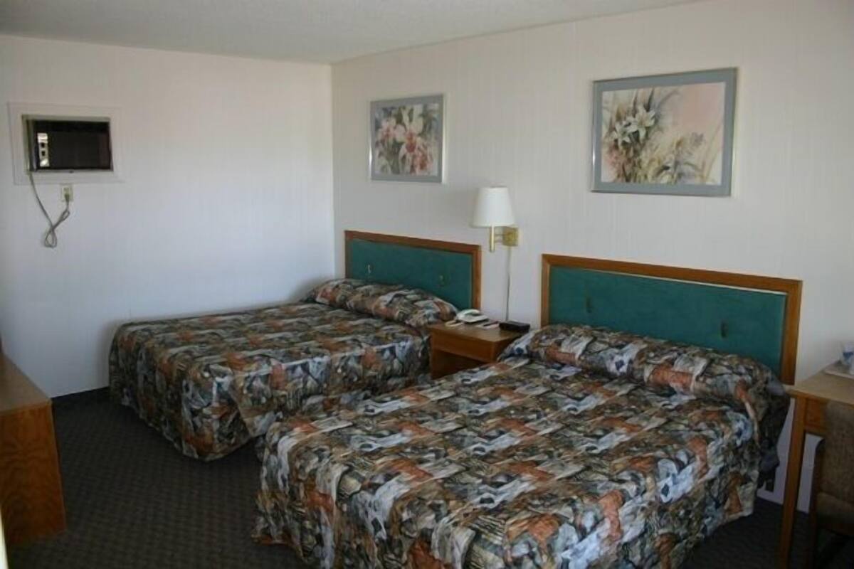 A hotel room with two beds, a TV, and artwork on the walls.