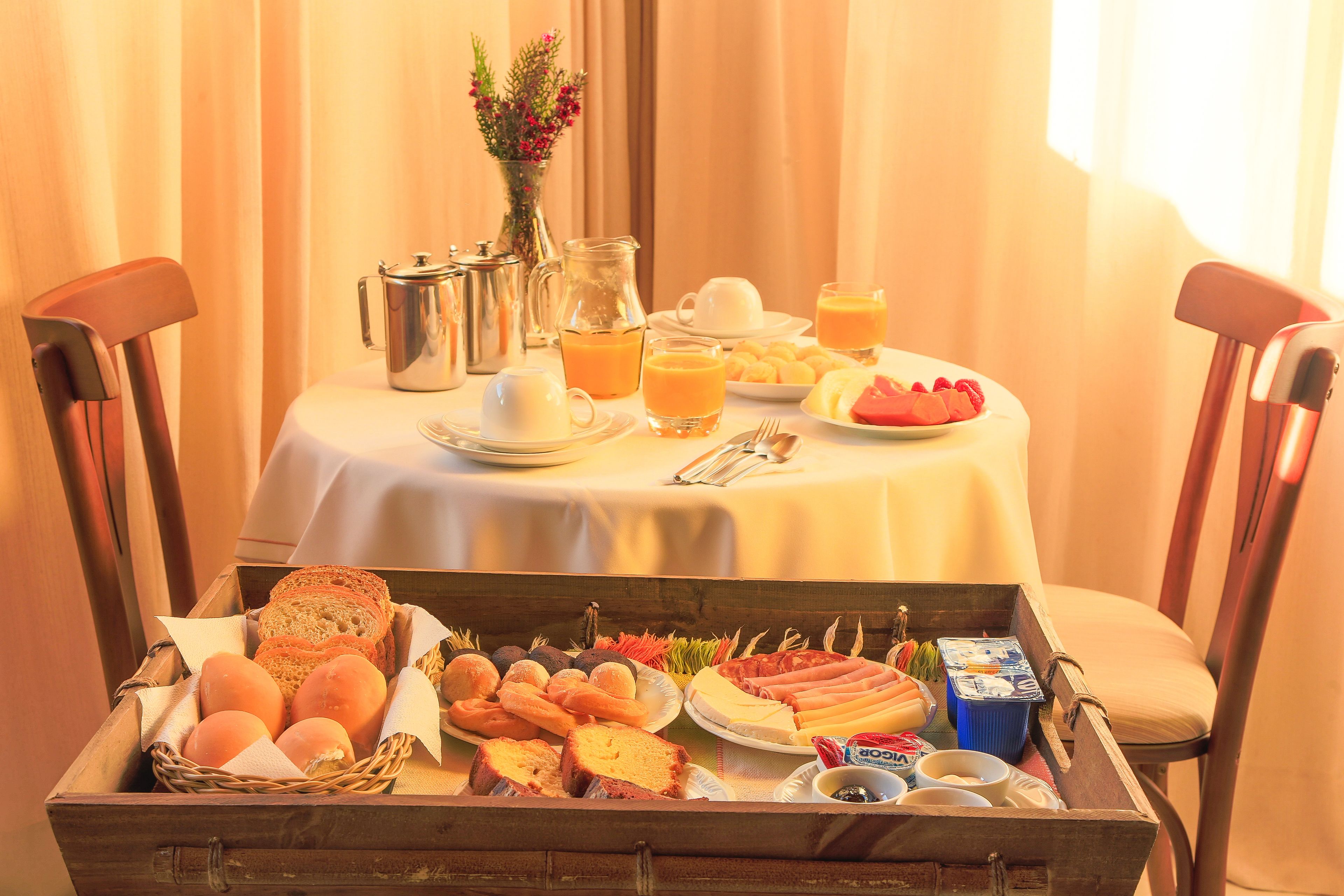 Un buffet de petit-déjeuner avec un assortiment de pains, de viennoiseries, de fruits et de boissons, le tout disposé sur une table.