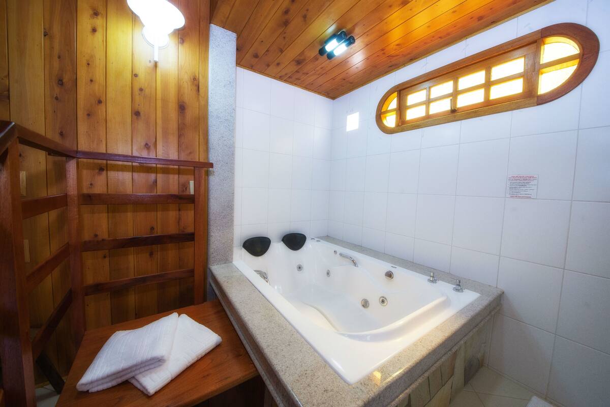 A wooden cabin-style bathroom with a large bathtub, wooden benches, and a towel rack.