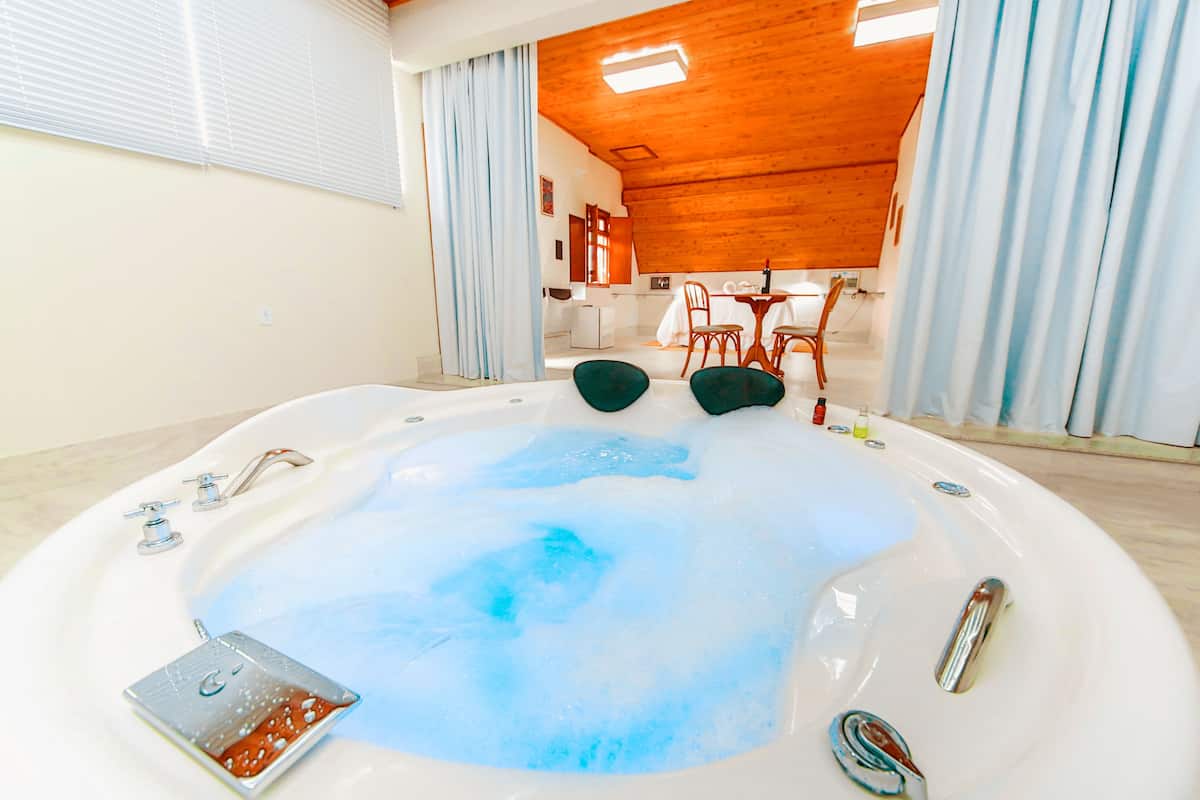 A hot tub with a wooden ceiling and a view of a dining area in the background.