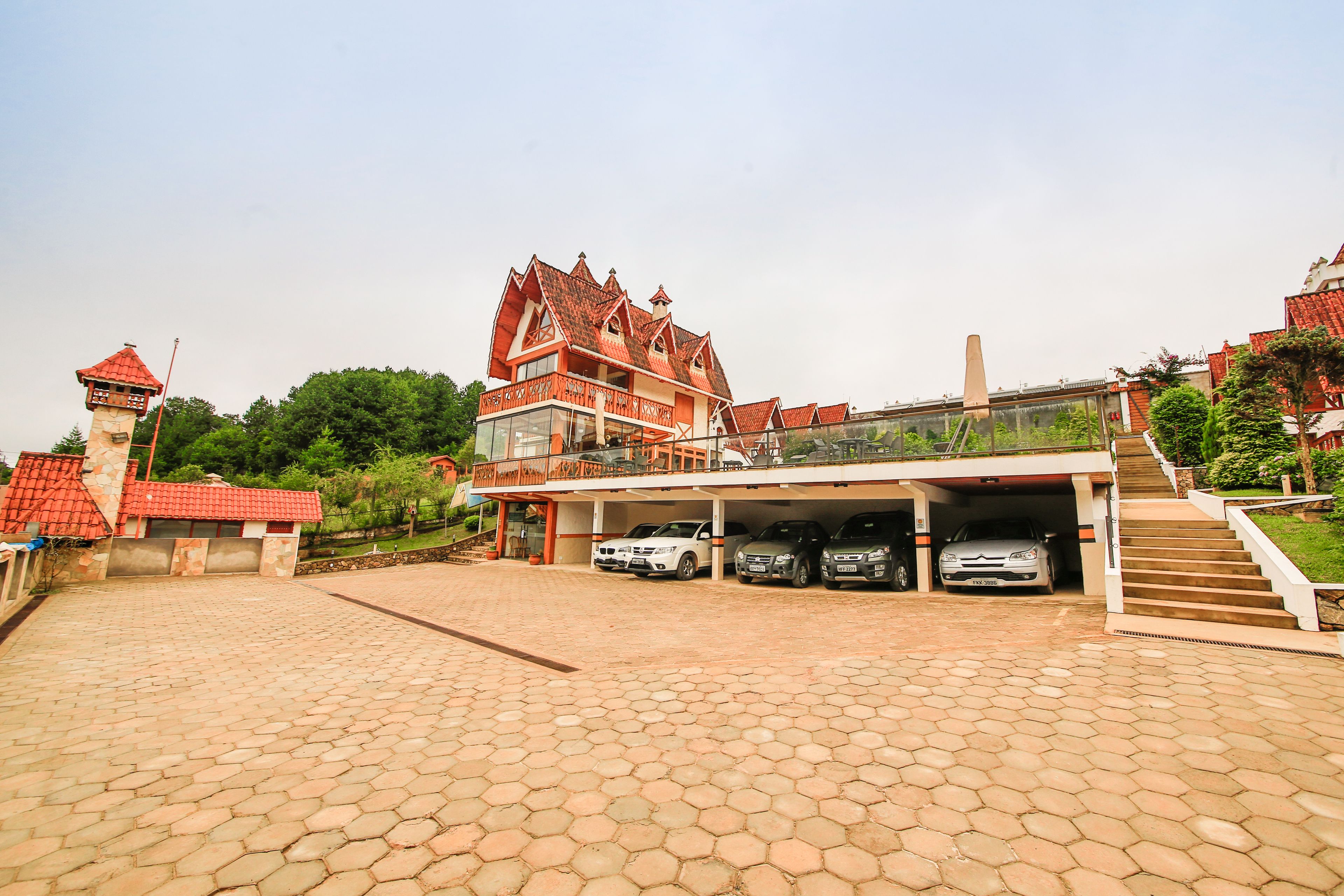 A large building with a red roof and multiple cars parked in a covered garage.