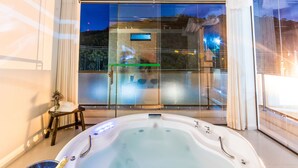 Un área de piscina interior moderna con un espacio acristalado, un jacuzzi y vistas al exterior.