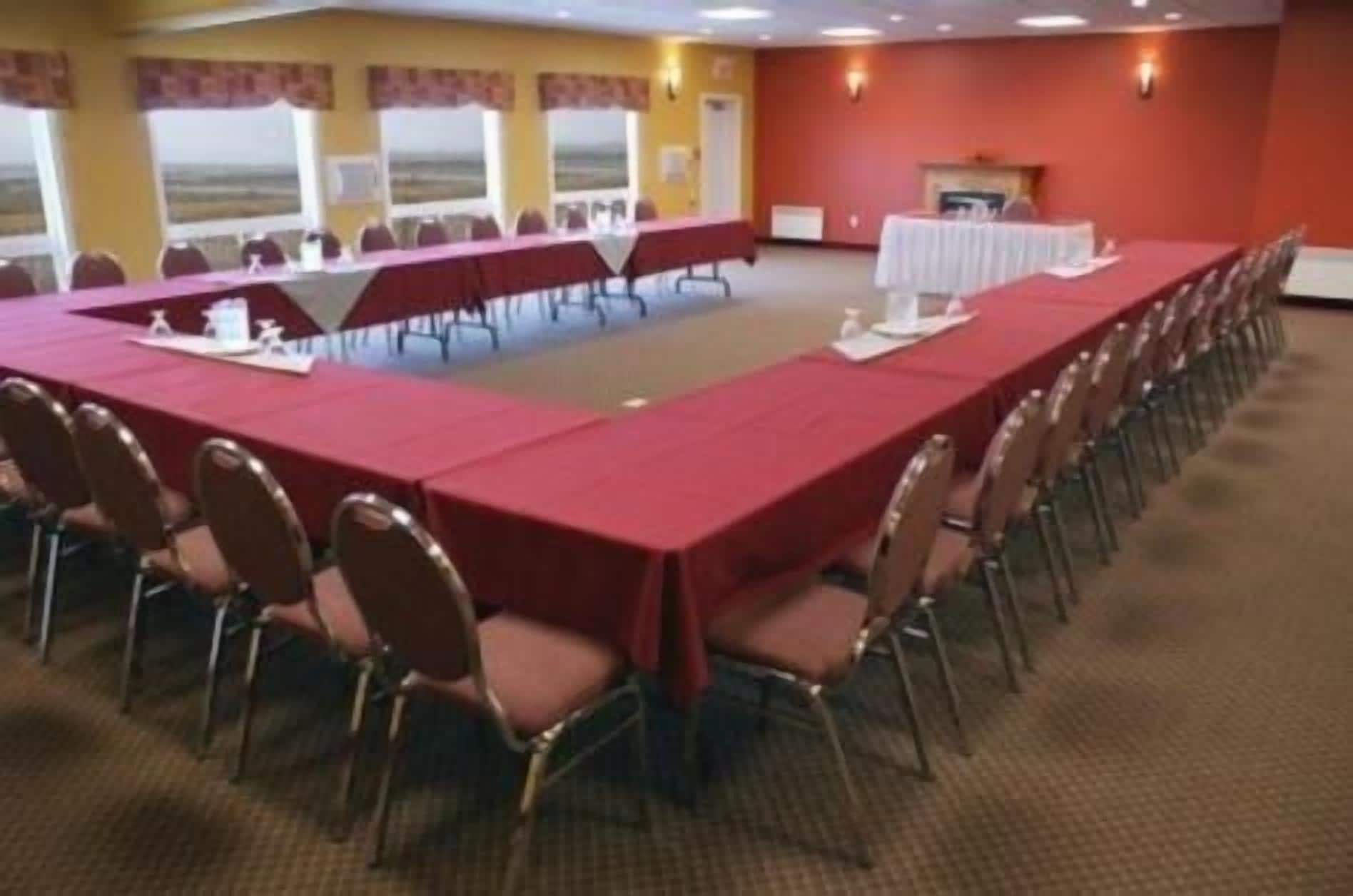 A conference room with a long table, chairs, and a view of the landscape through large windows.