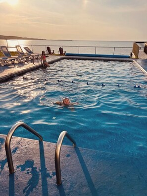 Una piscina al aire libre de temporada, sillones reclinables de piscina