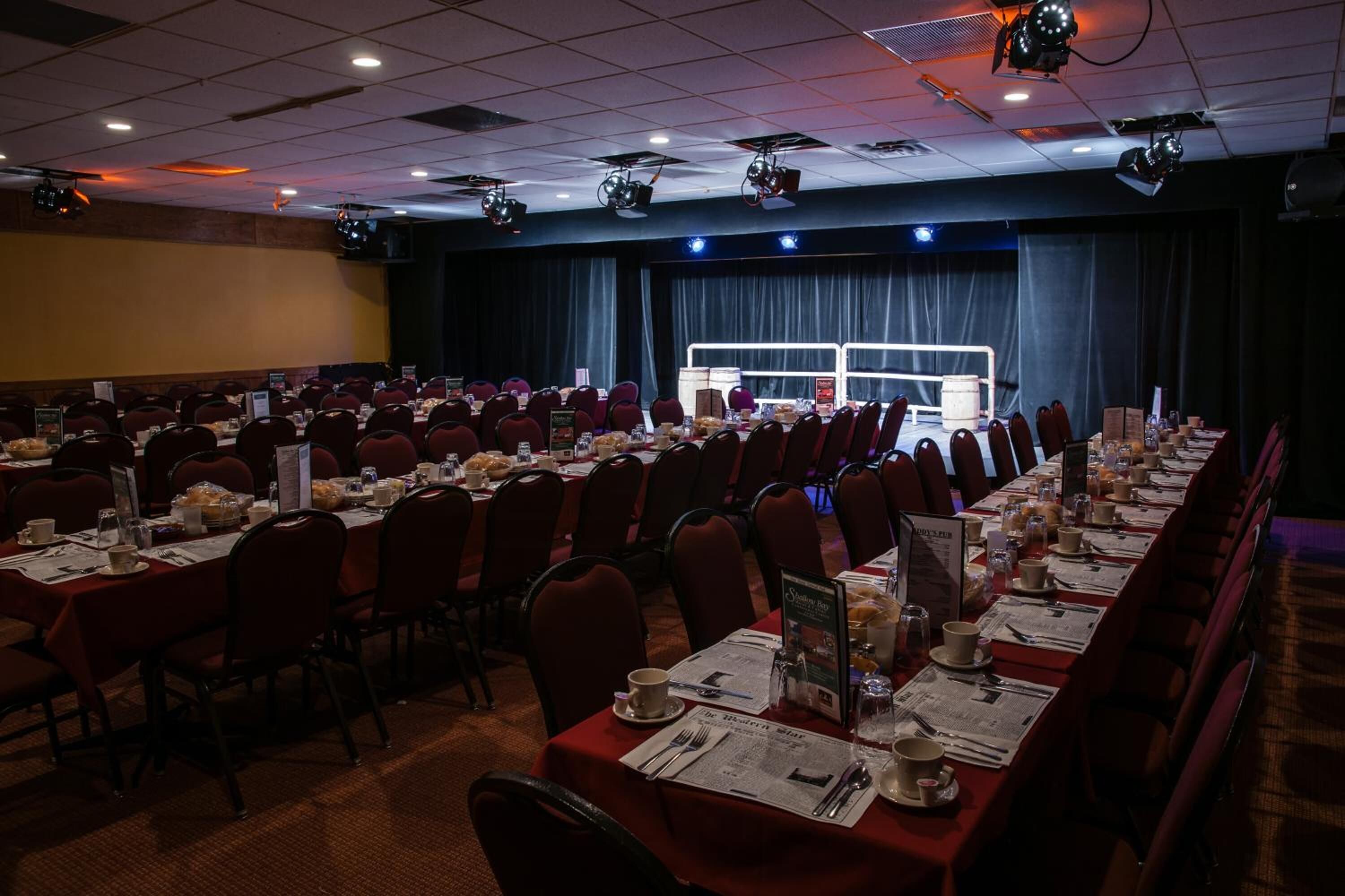 A conference room with rows of tables set for a meeting, equipped with nameplates, menus, and table settings.