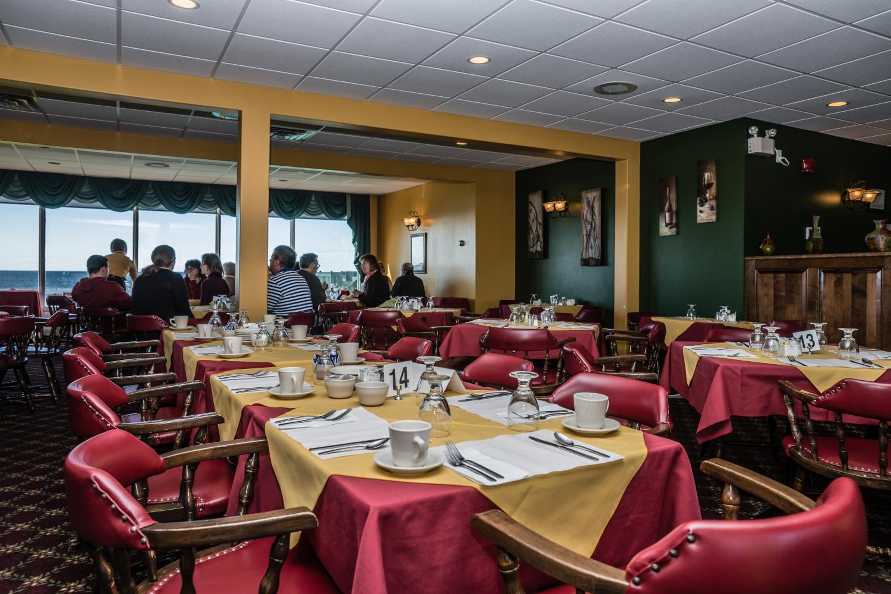 A restaurant with tables set for dining, numbered seating, and a view of the sea.