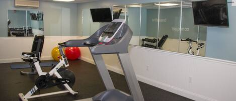 A gym with a treadmill, exercise balls, and weights.