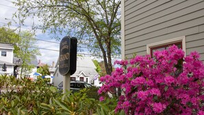 A sign for the Grand Hotel Bar Harbor, surrounded by lush greenery and pink bougainvillea flowers. - Bar Harbor Grand Hotel (Bar Harbor)