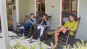 Three people seated on wooden benches outside a building with windows and a door. - Bar Harbor Grand Hotel (Bar Harbor)