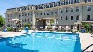 A hotel with a swimming pool, outdoor seating, and a covered walkway. - Bar Harbor Grand Hotel (Bar Harbor)