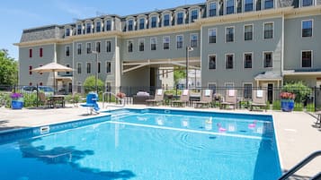 Una piscina al aire libre, sombrillas, sillones reclinables de piscina