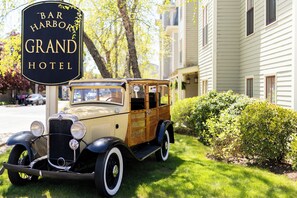 A vintage car parked in front of a hotel with a sign that reads 'Bar Harbor Grand Hotel.' - Bar Harbor Grand Hotel (Bar Harbor)