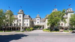 A large, historic hotel with multiple stories, a covered entrance, and red flags on the roof. - Bar Harbor Grand Hotel (Bar Harbor)