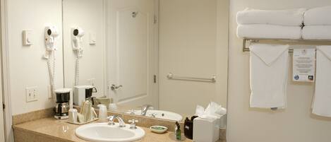 A hotel bathroom with a sink, mirror, towel rack, and a hairdryer.