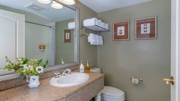 A bathroom with a sink, mirror, toilet, and towel rack.