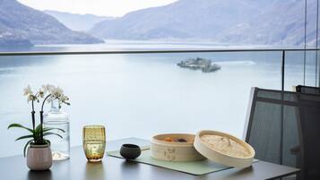 Una mesa con un jarrón de orquídeas, una copa y un juego de té tradicional, con un lago y montañas al fondo.