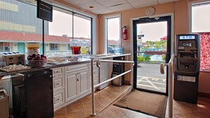 A small cafe with a counter, a refrigerator, a coffee machine, and an ATM. - Economy Motel Inn & Suites (Somers Point)