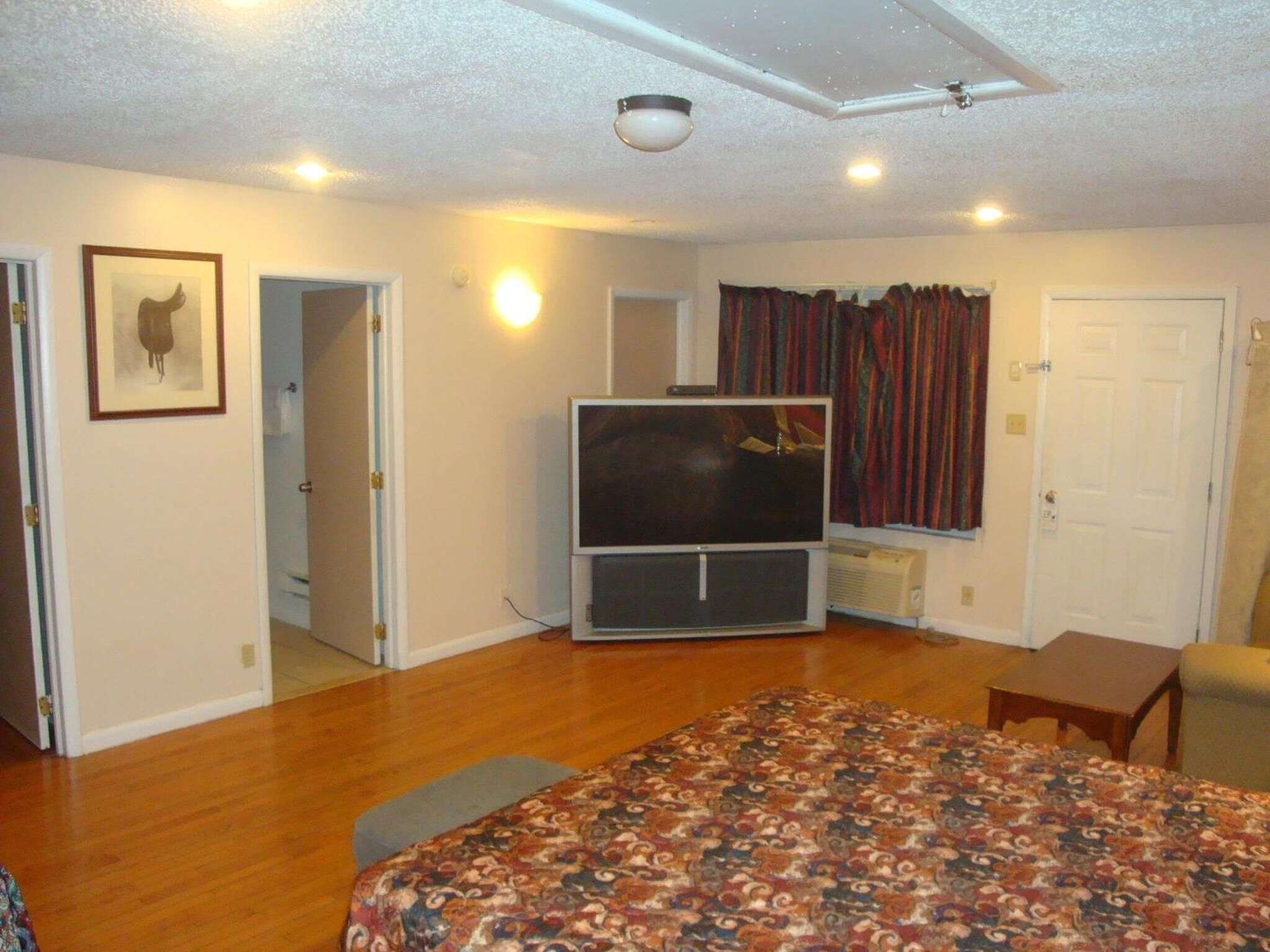 Une chambre d’hôtel avec un grand lit, un téléviseur à écran plat, une petite table et une chaise.