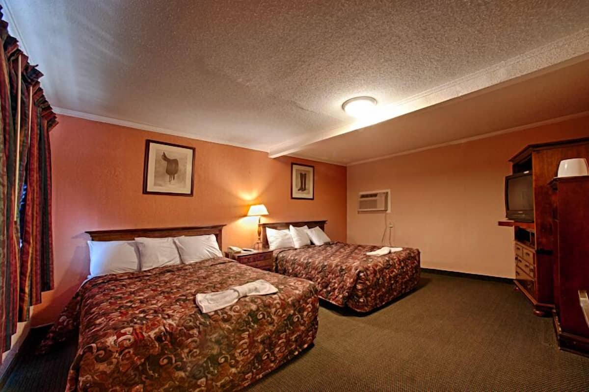 A hotel room with two beds, a television, and a cabinet.