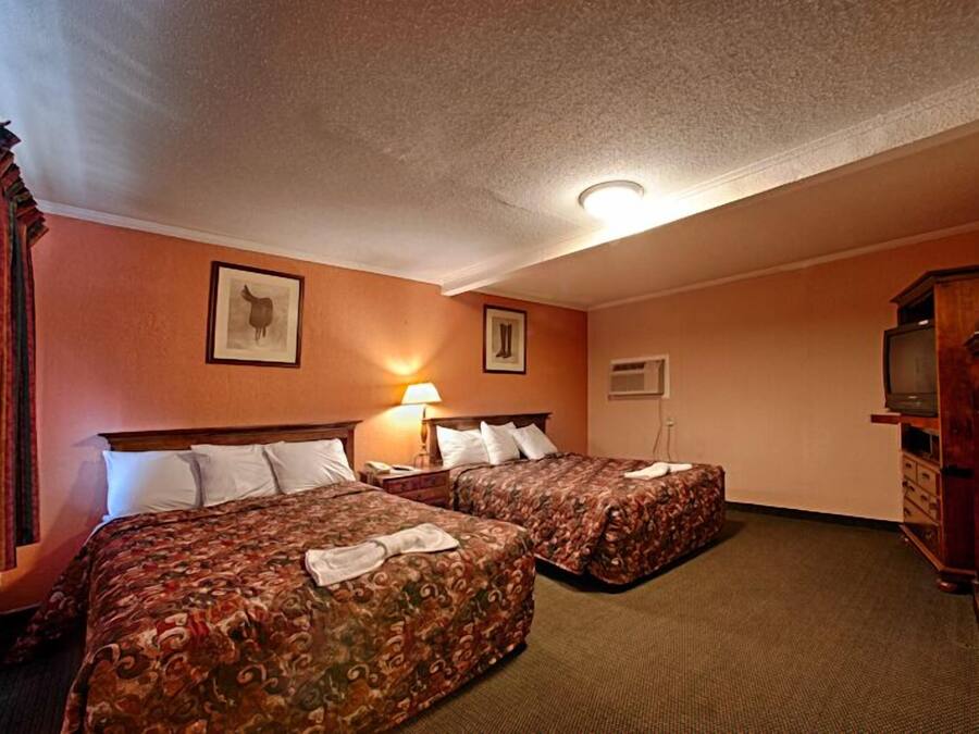 Een hotelkamer met twee bedden, een televisie en een kast.