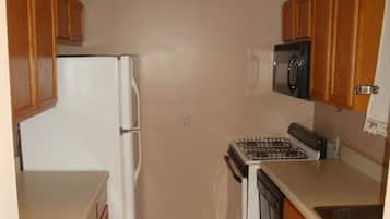 Una cocina compacta con armarios de madera, un refrigerador blanco, un microondas y una estufa.