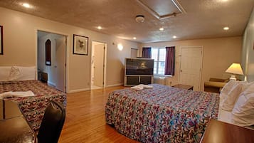 Una habitación de hotel con dos camas, televisión, escritorio y una silla.