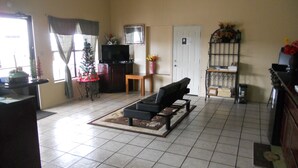 Un salon avec un canapé, une télévision, une petite table et un sapin de Noël.