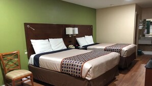 Une chambre d’hôtel avec deux lits, des têtes de lit en bois, une chaise et un petit bureau.