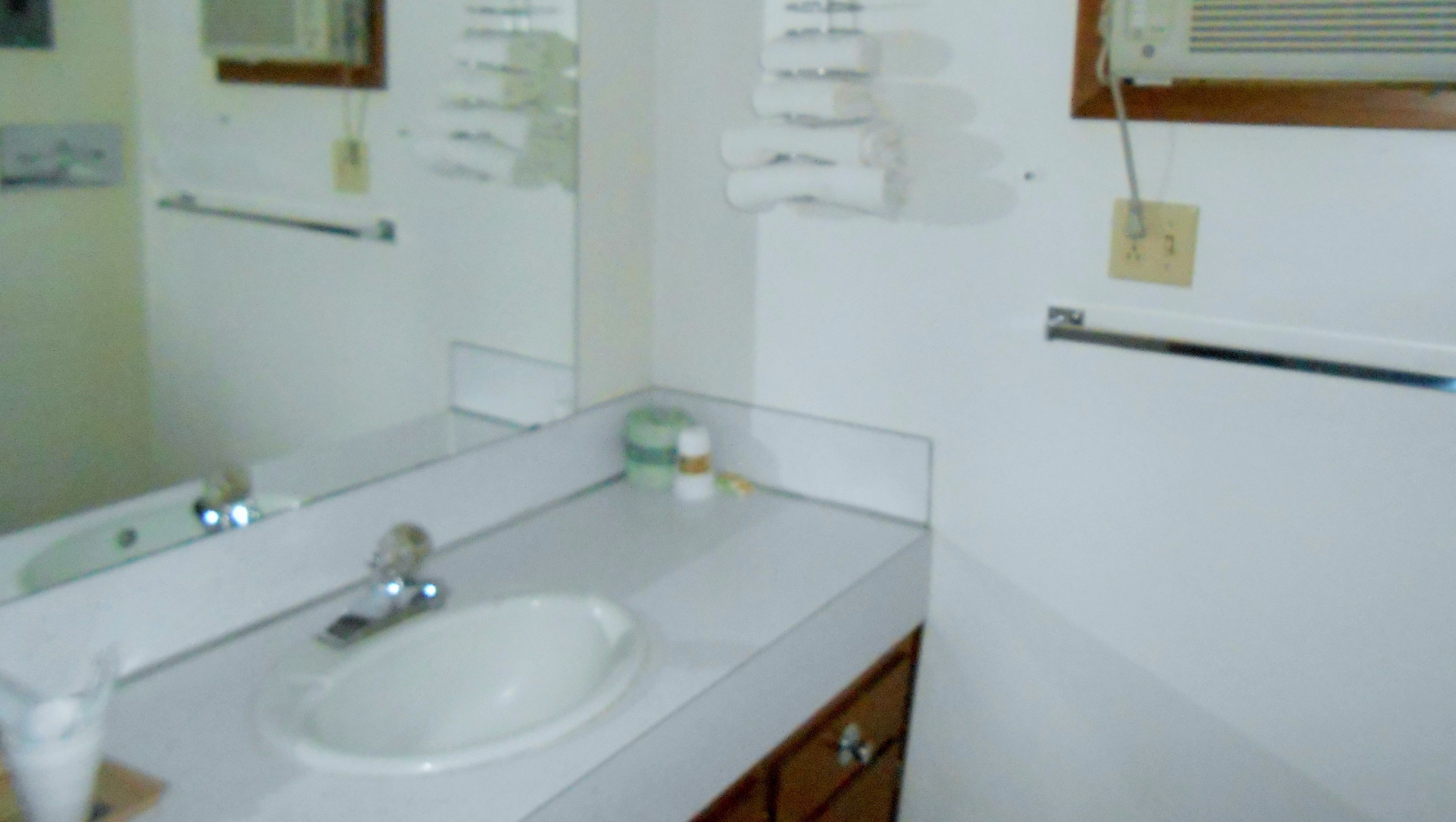 Un baño con lavamanos, espejo y toallero.