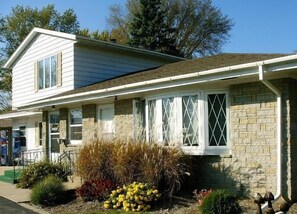 A two-story house with a stone facade and a front porch. - Budget Inn Long Praire (Long Prairie)