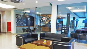 A modern lounge area with leather seating, a coffee table, and a glass partition. - d'primahotel ITC Mangga Dua (Jakarta)