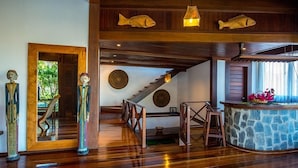 A spacious room with wooden floors, a stone bar, and a staircase leading to another level. - Sombra e Água Fresca Resort (Tibau do Sul)
