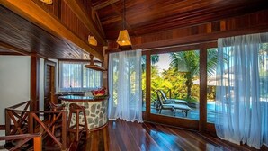 A wooden interior with a bar area, large windows, and a view of an outdoor pool area. - Sombra e Água Fresca Resort (Tibau do Sul)