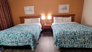 Une chambre d’hôtel avec deux lits, chacun recouvert d’une couvre-lit à motifs floraux. Il y a deux tables de chevet avec des lampes et un téléphone.