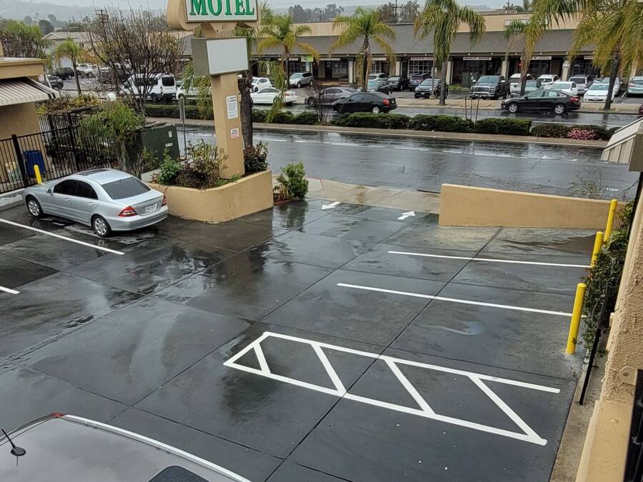 A parking lot with a sign for Harvey's Motel, multiple parked cars, and a wet pavement indicating recent rain.