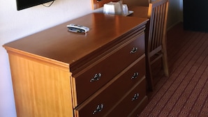 Une commode en bois avec des tiroirs, un miroir et un téléviseur fixé au mur.