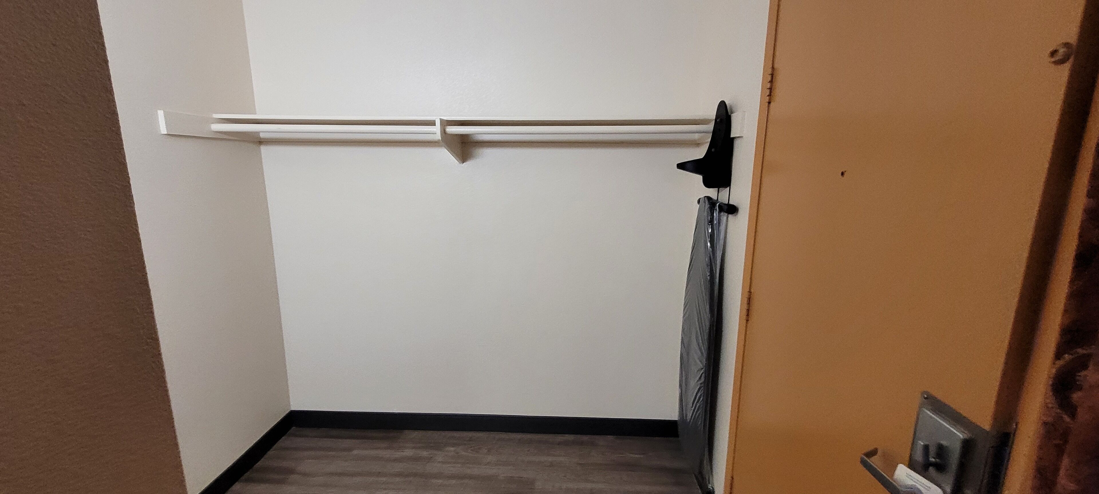 Ein schmaler Flur mit einer weißen Tür, einem Heizkörper und einem schwarzen Gegenstand an der Wand.