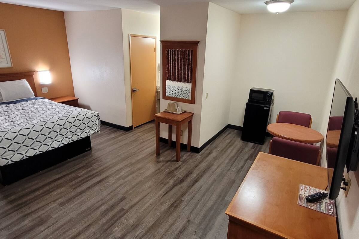A hotel room with a bed, a desk, a chair, a television, and a microwave.