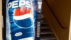 Un distributeur automatique orné du logo Pepsi, situé près d’un escalier.
