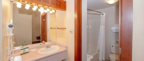 A bathroom with a wooden vanity, a large mirror, and a shower area.