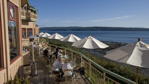 An outdoor seating area with tables and chairs, umbrellas, and a view of the water.