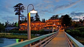 A wooden bridge leading to a lodge with multiple balconies and warm lighting.