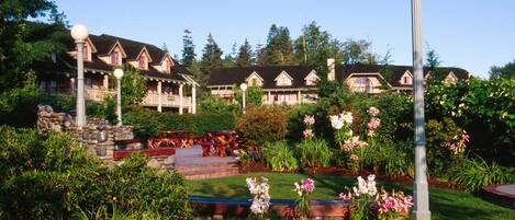 A hotel with multiple buildings, a well-maintained garden with flowers, and outdoor seating areas.