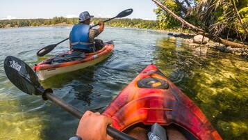A kayak on a calm river with clear water and trees on the bank.