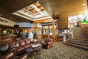 Welcome to the grand lobby, featuring a reception desk, comfortable seating area, and a staircase leading to an upper level.